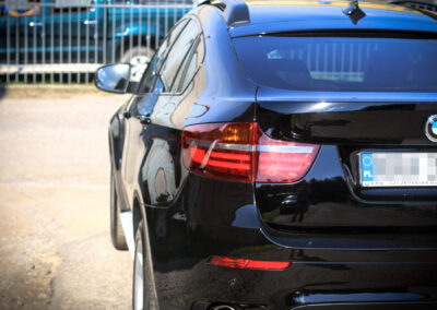 Zbliżenie na tylną klapę bagażnika oraz lampy czarnego BMW x6 po wykonaniu serwisu powłoki ceramicznej